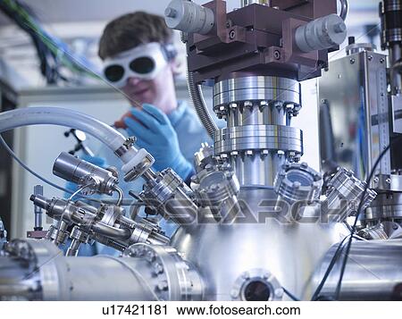Stock Image - Scientist using vacuum chamber in lab. Fotosearch