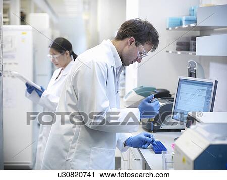 Stock Image - Scientists piping liquid into tubes. Fotosearch