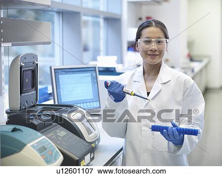 Stock Photo - Scientists piping liquid into tubes. Fotosearch