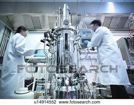 Stock Image - Scientists working with equipment in lab. Fotosearch