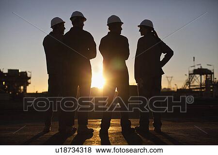 Stock Photo - Silhouette of workers at oil refinery. Fotosearch
