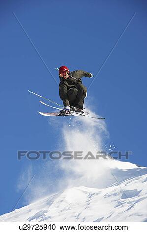 Stock Image - Skier jumping off snowy slope. Fotosearch