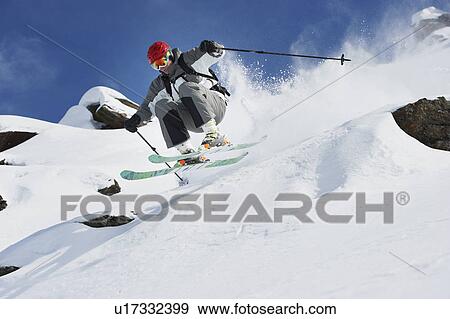 Stock Photo - Skier jumping off snowy slope. Fotosearch
