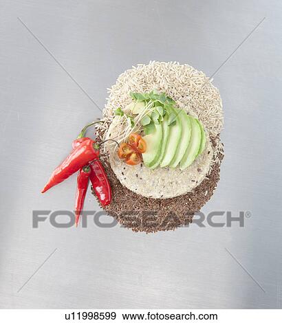 Stock Photo - Sliced avocado, peppers and grains with arepas (Colombian corn bread) made with quinoa. Fotosearch