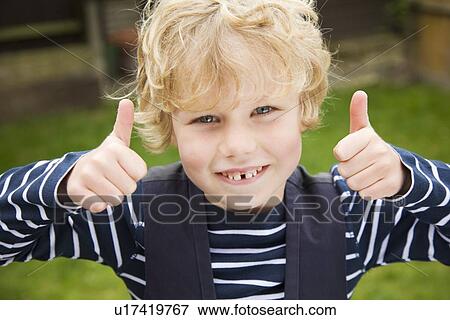 Stock Photo - Smiling boy giving thumbs-up outdoors. Fotosearch