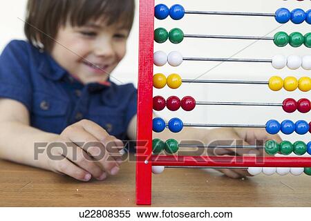 Stock Photography - Smiling boy playing with abacus. Fotosearch