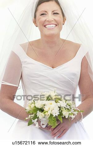 Stock Photograph - Smiling bride holding bouquet. Fotosearch