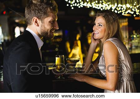 Stock Photograph - Smiling couple having drinks at bar. Fotosearch