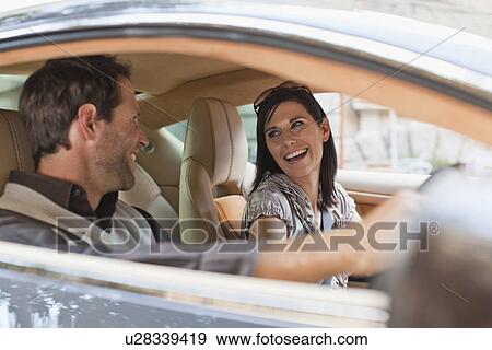 Stock Photo - Smiling couple talking in sports car. Fotosearch