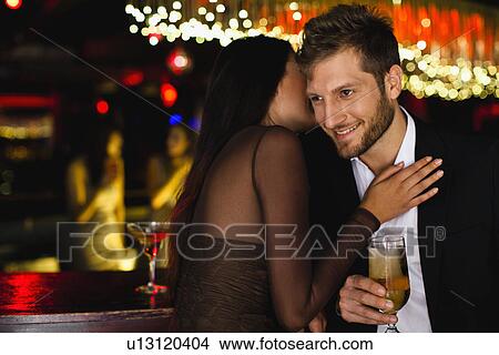 Smiling couple whispering at bar View Large Photo Image Picture - Smiling couple whispering at bar. Fotosearch
