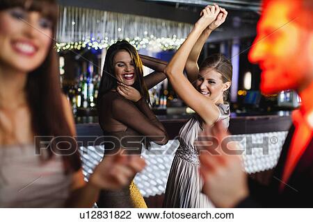Stock Image - Smiling friends dancing in bar. Fotosearch