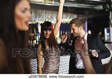 Stock Photo - Smiling friends dancing in bar. Fotosearch