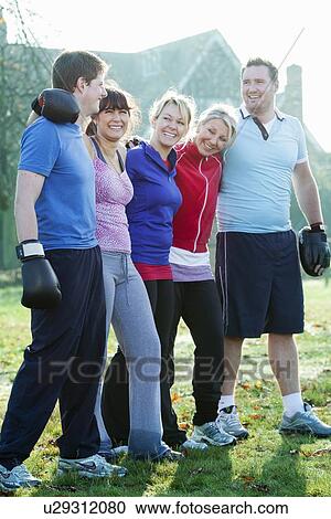Stock Image - Smiling friends hugging outdoors. Fotosearch