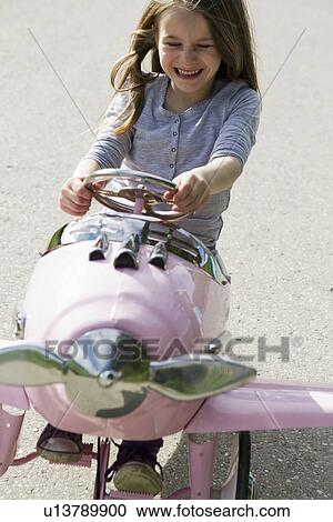 Stock Image - Smiling girl driving toy airplane. Fotosearch