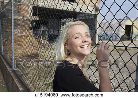 Smiling girl leaning against fence View Large Photo Image Stock Image - Smiling girl leaning against fence. Fotosearch
