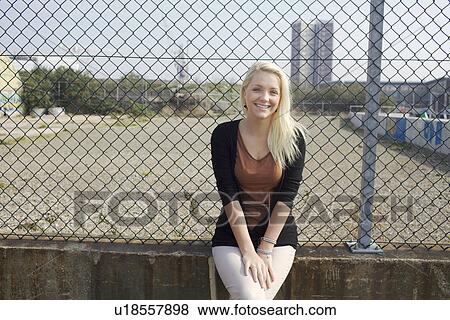 Smiling girl leaning against fence View Large Photo Image Stock Photo - Smiling girl leaning against fence. Fotosearch