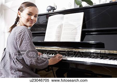 Stock Photography - Smiling girl practicing at piano. Fotosearch