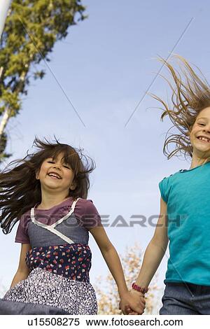 Smiling girls holding hands outdoors View Large Photo Image Stock Photography - Smiling girls holding hands outdoors. Fotosearch