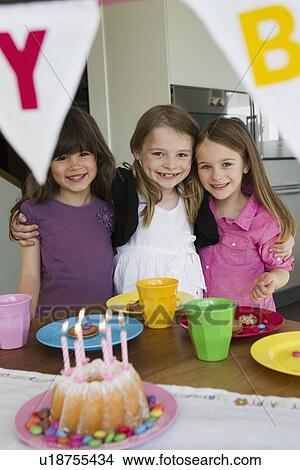 Picture - Smiling girls hugging at birthday party. Fotosearch