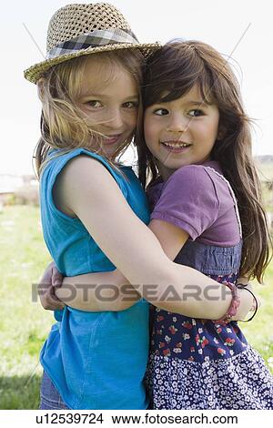 Picture - Smiling girls hugging outdoors. Fotosearch