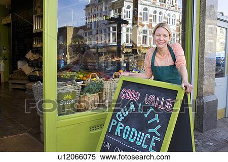 Smiling grocer standing outside store View Large Photo Image Stock Photography - Smiling grocer standing outside store. Fotosearch