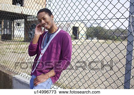 Smiling man leaning against fence View Large Photo Image Stock Image - Smiling man leaning against fence. Fotosearch