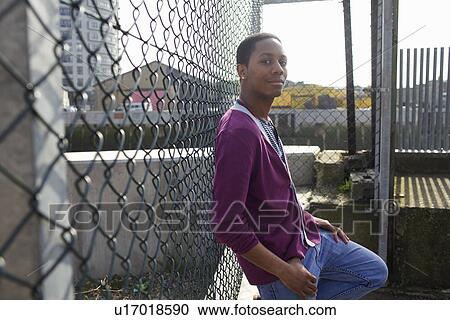Smiling man leaning against fence View Large Photo Image Stock Image - Smiling man leaning against fence. Fotosearch