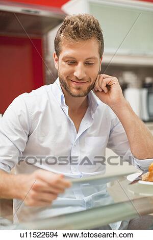 Smiling man reading at table View Large Photo Image Picture - Smiling man reading at table. Fotosearch