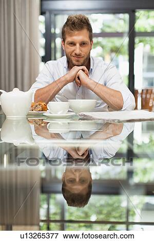 Smiling man sitting at breakfast View Large Photo Image Stock Photo - Smiling man sitting at breakfast. Fotosearch