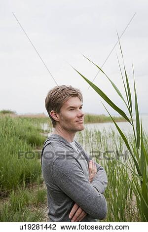 Smiling man standing on grassy beach View Large Photo Image Stock Image - Smiling man standing on grassy beach. Fotosearch