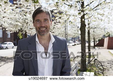 Smiling man standing under tree View Large Photo Image Stock Photo - Smiling man standing under tree. Fotosearch