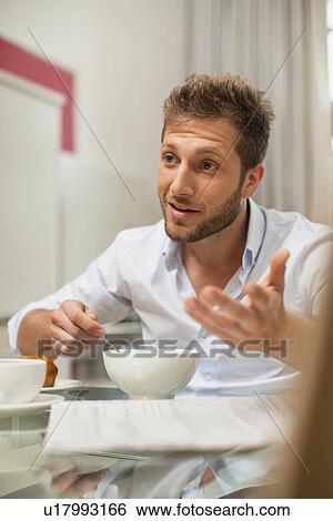 Stock Photograph - Smiling man talking at breakfast. Fotosearch