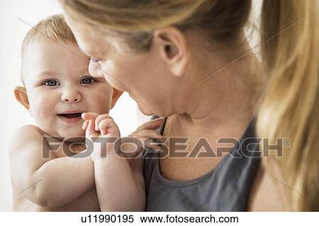 Stock Photography - Smiling mother holding baby girl. Fotosearch