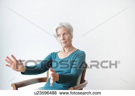 Smiling older woman reaching in chair View Large Photo Image Stock Photo - Smiling older woman reaching in chair. Fotosearch