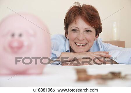 Smiling woman admiring piggy bank View Large Photo Image Stock Photography - Smiling woman admiring piggy bank. Fotosearch