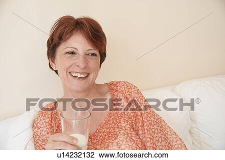 Stock Image - Smiling woman drinking glass of milk. Fotosearch
