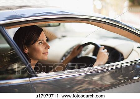 Stock Image - Smiling woman driving sports car. Fotosearch