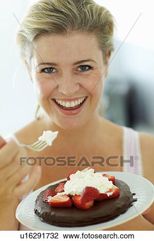 Smiling woman eating cake in kitchen View Large Photo Image Stock Image - Smiling woman eating cake in kitchen. Fotosearch