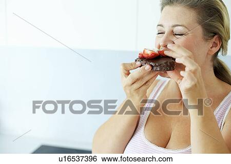 Stock Photograph - Smiling woman eating cake. Fotosearch