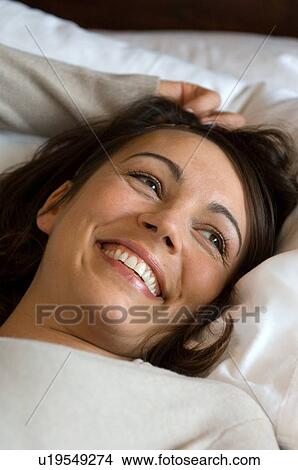 Smiling woman laying in bed View Large Photo Image Picture - Smiling woman laying in bed. Fotosearch