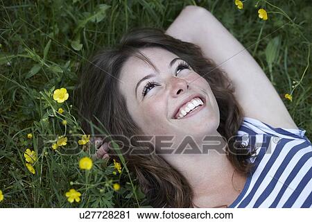 Smiling woman laying in grass View Large Photo Image Stock Image - Smiling woman laying in grass. Fotosearch