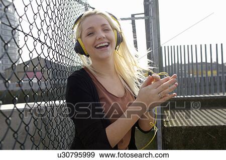 Smiling woman listening to headphones View Large Photo Image Stock Photo - Smiling woman listening to headphones. Fotosearch