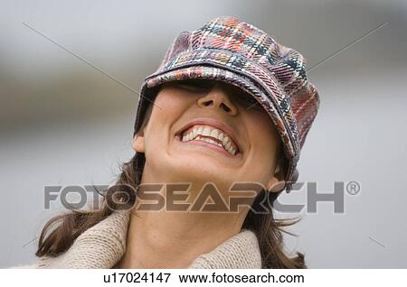 Smiling woman peering from under cap View Large Photo Image Stock Photo - Smiling woman peering from under cap. Fotosearch