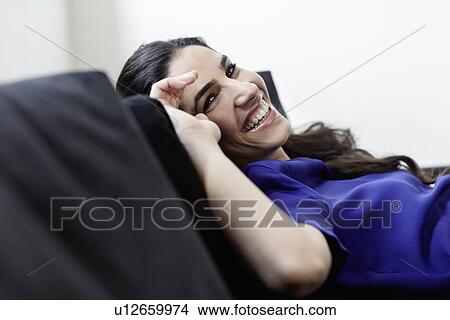 Picture - Smiling woman relaxing on sofa. Fotosearch