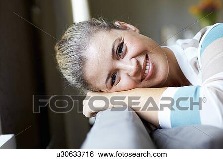 Smiling woman relaxing on sofa View Large Photo Image Stock Photograph - Smiling woman relaxing on sofa. Fotosearch