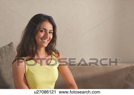 Smiling woman sitting on sofa View Large Photo Image Stock Image - Smiling woman sitting on sofa. Fotosearch
