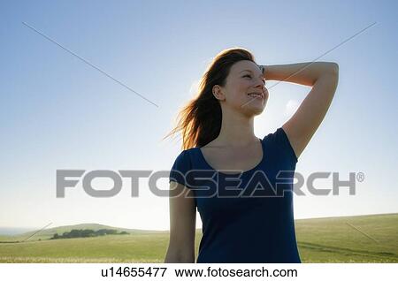 Smiling woman standing in field View Large Photo Image Stock Photo - Smiling woman standing in field. Fotosearch