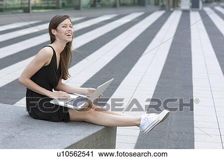 Smiling woman using laptop outdoors View Large Photo Image Stock Image - Smiling woman using laptop outdoors. Fotosearch