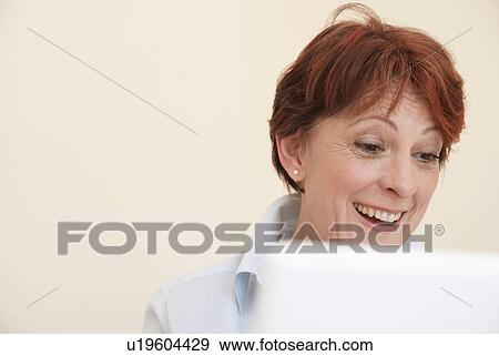 Smiling woman using laptop View Large Photo Image Stock Photo - Smiling woman using laptop. Fotosearch