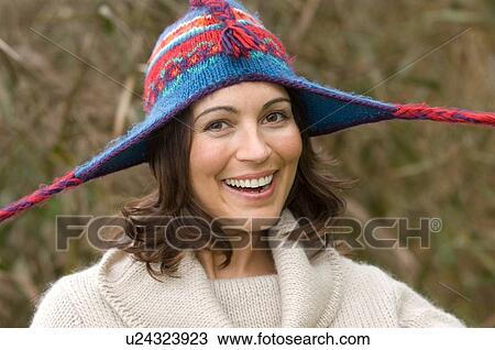 Stock Image - Smiling woman wearing knitted hat. Fotosearch